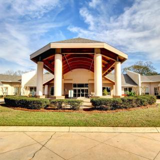 A modern building with a prominent entrance and columns under a partly cloudy sky.