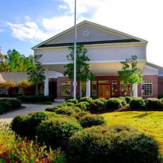 A well-maintained building surrounded by lush landscaping and greenery on a sunny day.