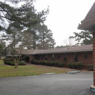 A view of a brick building surrounded by greenery, showcasing a calm and quiet environment.