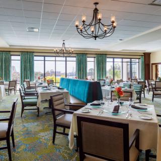 A spacious and elegantly set dining room with multiple tables and chandeliers.