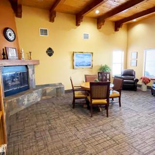 Cozy living room with a fireplace and wooden ceiling beams, featuring a dining table and comfortable seating.