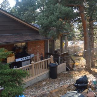 A cozy outdoor patio area with a grill, surrounded by trees.