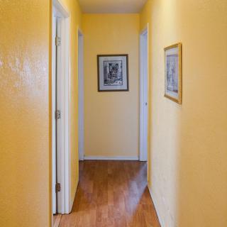 A brightly painted hallway with yellow walls, wooden floors, and framed artwork on the walls.