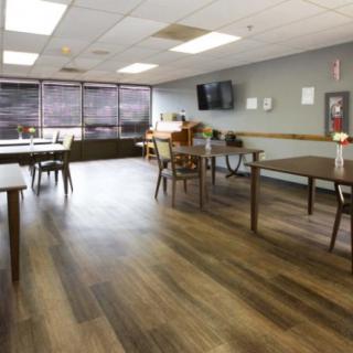 An empty dining area with wooden flooring, tables, and chairs.