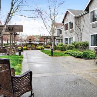 A charming apartment complex with a landscaped walkway and seating areas.