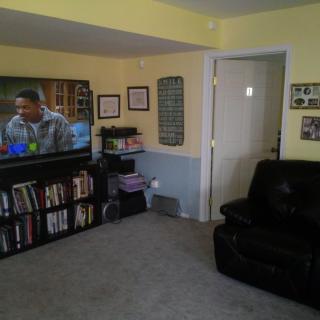 A cozy living room featuring a television, bookshelf, and comfortable seating.