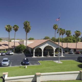 A sunny day view of a building with a parking lot and palm trees.