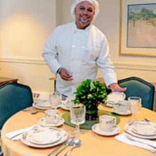 A chef proudly presents a well-set dining table in a restaurant.