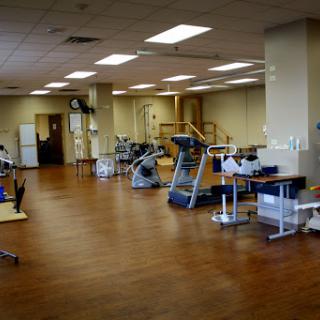 A spacious and well-lit physical therapy room equipped with various rehabilitation tools.