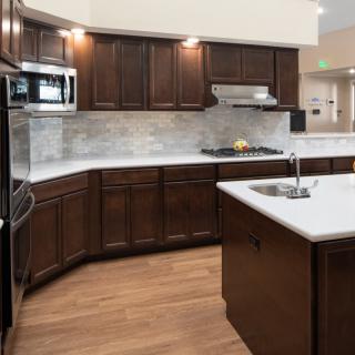 A modern kitchen with dark wood cabinets, a central island, and built-in appliances.