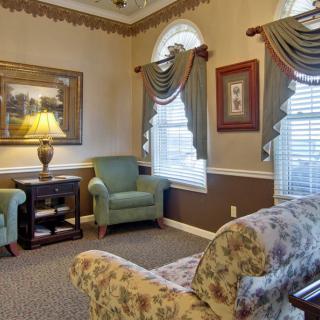 A cozy living room with armchairs, a sofa, and decorative curtains.
