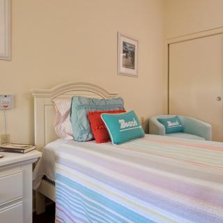 A cozy bedroom with a neatly made bed, colorful pillows, and simple decor.