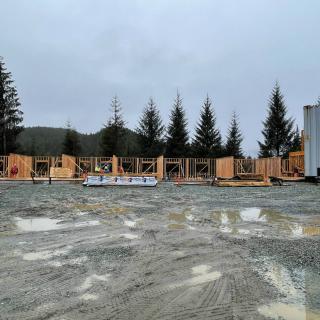 A construction site with wooden frames surrounded by trees on an overcast day.