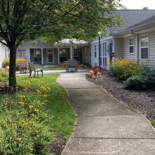 A landscaped garden with a concrete pathway and benches surrounded by buildings.