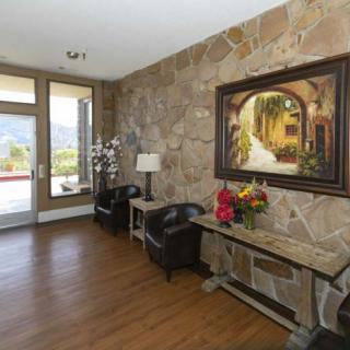 A warmly decorated entryway featuring a stone wall with a large painting, wood flooring, and stylish furniture.