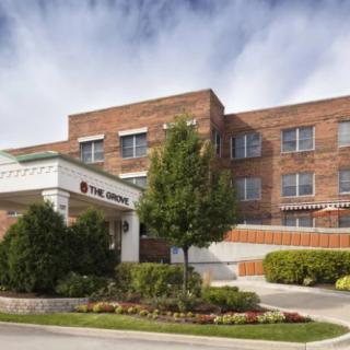 A brick healthcare building with a main entrance and surrounding greenery.