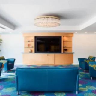 A modern lounge area with blue seating, a large television, and a colorful carpet.