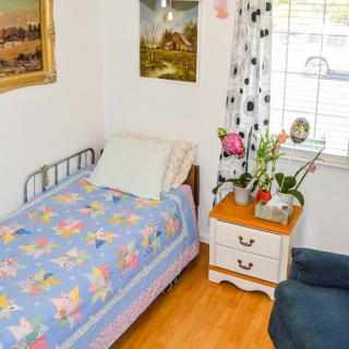 A cozy bedroom with a single bed, floral bedding, and a nightstand adorned with flowers.