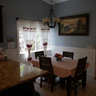 A cozy dining area with a table set for four, adorned with a chandelier and framed artwork.