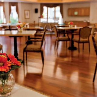 A cozy restaurant dining area with wooden floors and tables set with flowers.