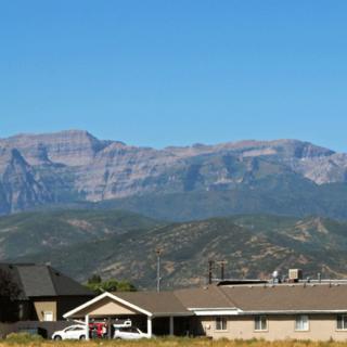A suburban area with houses in the foreground and a range of mountains in the background under a clear blue sky.