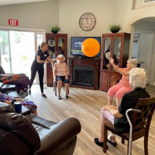 Seniors engaging in a fun exercise activity with a balloon, promoting physical fitness and social interaction.
