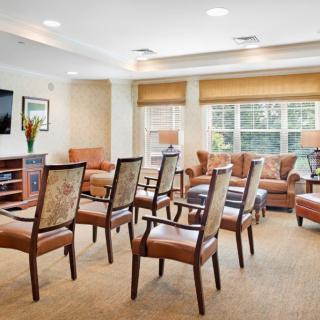 A well-lit living room with chairs arranged for a gathering.