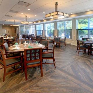 A spacious and well-lit dining area with neatly arranged tables and chairs, featuring large windows and stylish lighting.