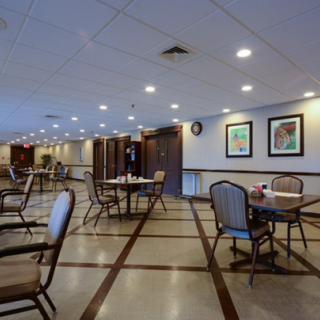 A spacious dining area with neatly arranged tables and chairs, adorned with wall art and ample lighting.