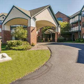 A residential building with a covered driveway entrance, surrounded by well-maintained landscaping.