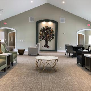 A spacious and inviting community lounge featuring comfortable seating and a decorative tree mural.