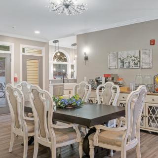 An elegant dining room with a dark wooden table surrounded by ornate chairs, adorned with tasteful decor and a modern chandelier.