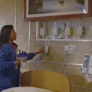 A nurse adjusts equipment in a hospital patient room.
