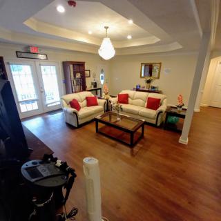A cozy living room featuring white sofas with red cushions, a wooden coffee table, and wood flooring.