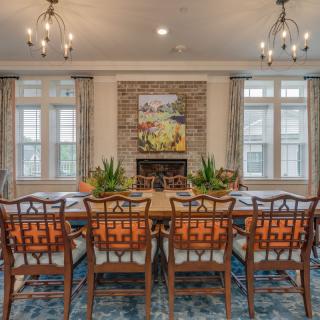 Elegant dining room with a large table and chandeliers, featuring a fireplace and artwork.