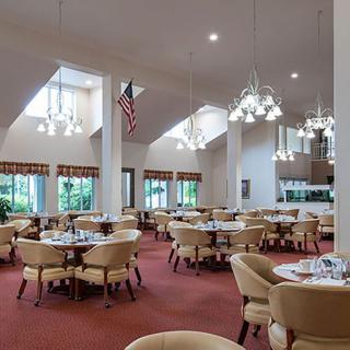 An elegantly designed dining area featuring multiple tables and plush seating, illuminated by chandeliers.