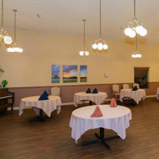 An elegant dining room with round tables, neatly arranged table settings, and soft lighting.