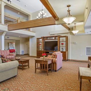 A cozy living room with sofas, wooden beams, and chandeliers.