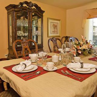 A dining room with a table set for a meal, complete with plates, cups, and a floral centerpiece.
