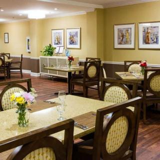 A well-decorated dining area with tables and chairs, adorned with flowers and artwork on the walls.