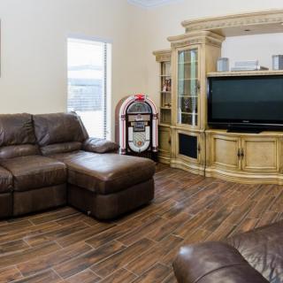A cozy living room featuring a leather sectional, flat screen TV, and a classic jukebox.