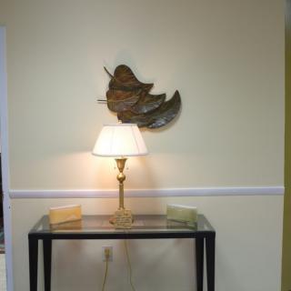 A cozy interior setup featuring a table lamp and decorative wall art above a glass-topped table.
