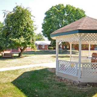 A peaceful park setting featuring a gazebo surrounded by trees and grassy areas.