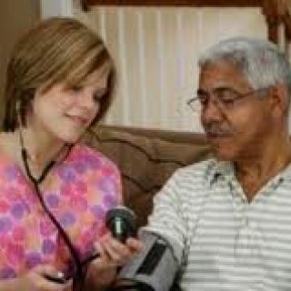 A nurse taking the blood pressure of an elderly man in a home setting.
