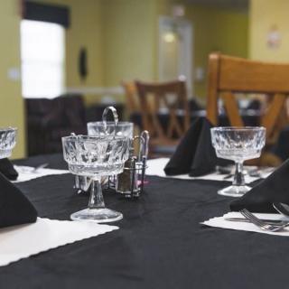 A dining table set in a restaurant with crystal glasses and black napkins.