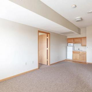An empty apartment interior with a small kitchen area.