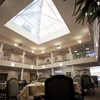 An interior view of a spacious dining area with a skylight atrium, surrounded by tables and chairs.
