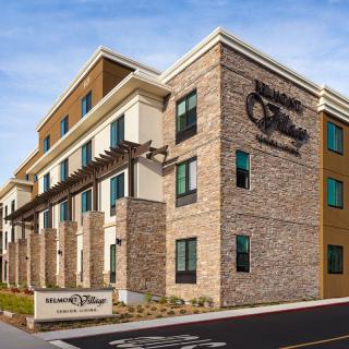 A modern hotel building with stone and brick facade under a clear blue sky.