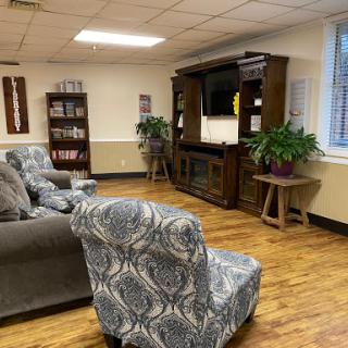 A cozy lounge area featuring comfortable seating, bookshelves filled with books, and a TV stand.