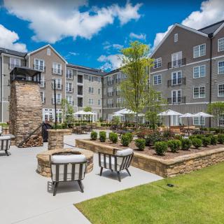 A well-maintained apartment courtyard featuring a spacious seating area and elegant landscaping on a sunny day.